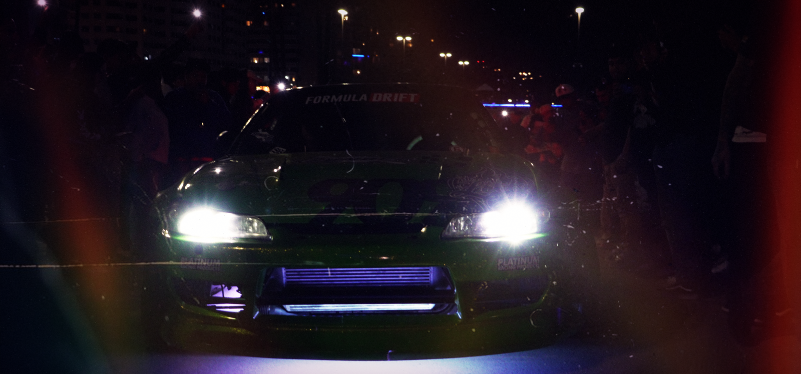 SKYSPECS Digital automotive visual study showing a green drift car with cinematic headlights and night-event atmosphere